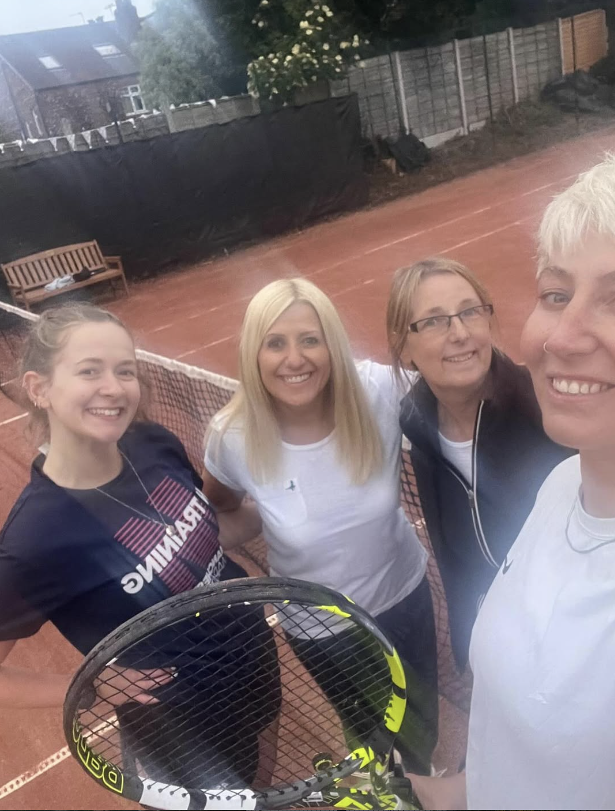 Four women smiling together on the Claremont clay tennis courts
