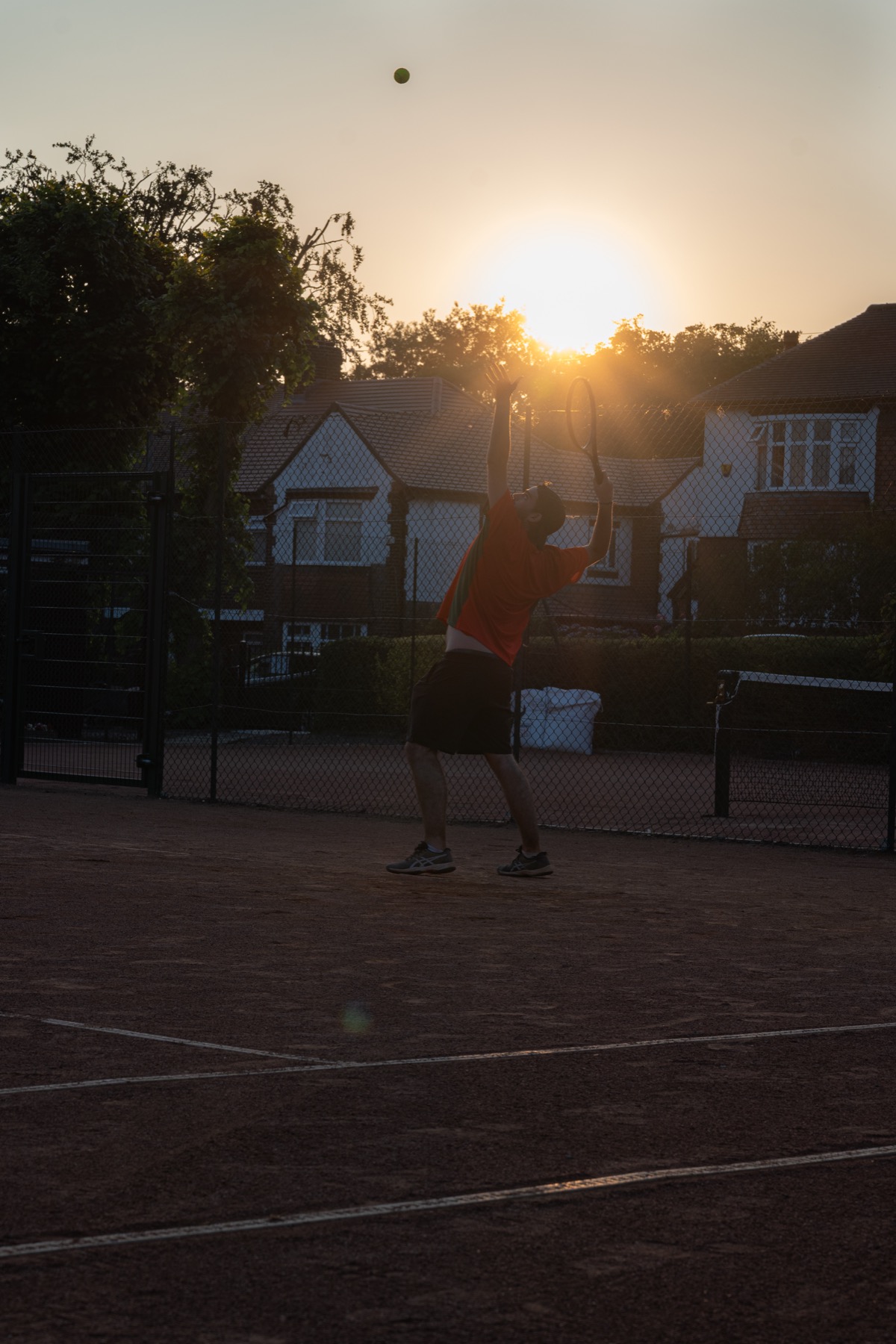 A player serving during evening tennis at Claremont