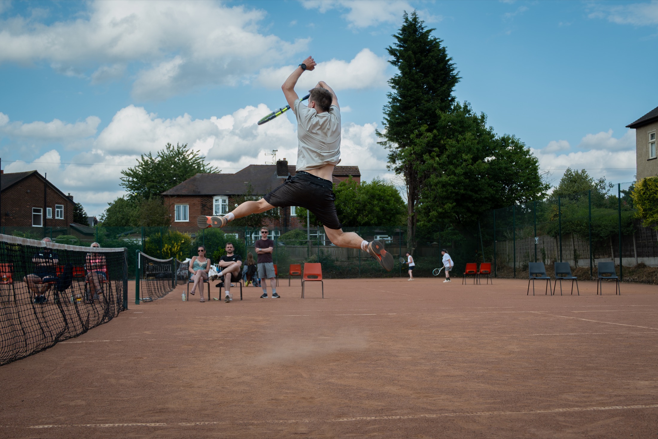 A Claremont player jumping to hit a shot on the clay courts